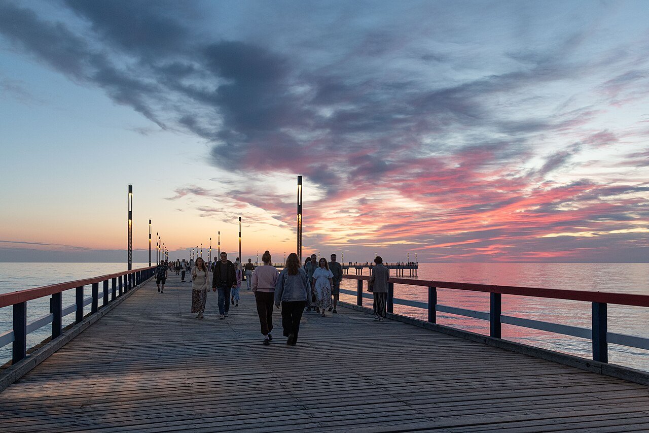 People walking along Palanga Pier under a Baltic sunset